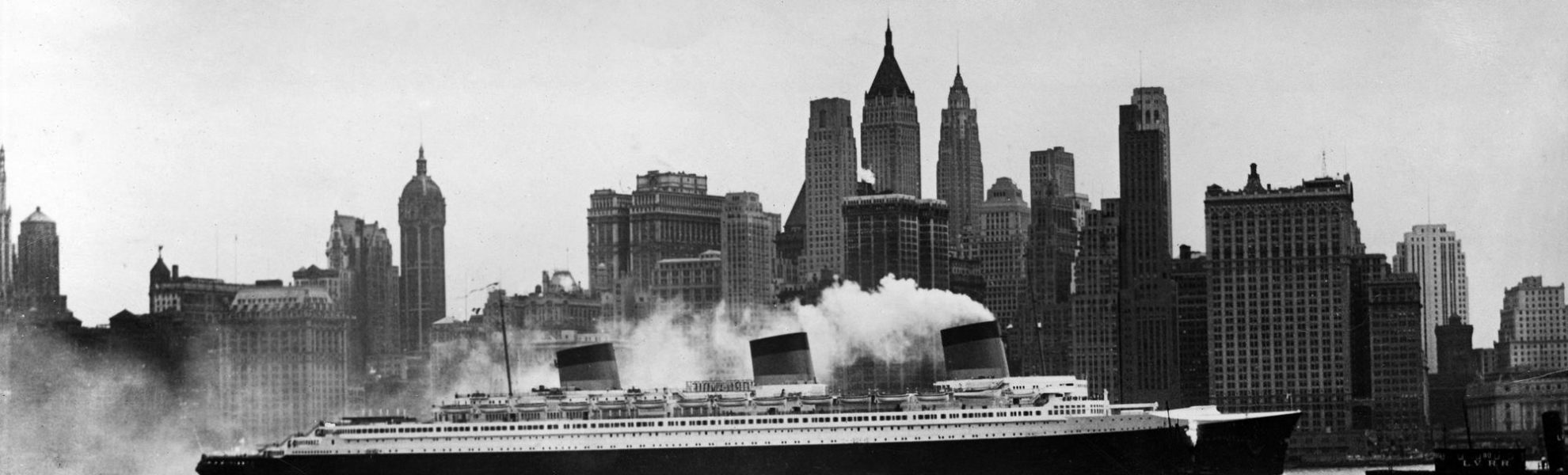 Photographie en noir et blanc représentant le paquebot Normandie devant les immeubles à New York.