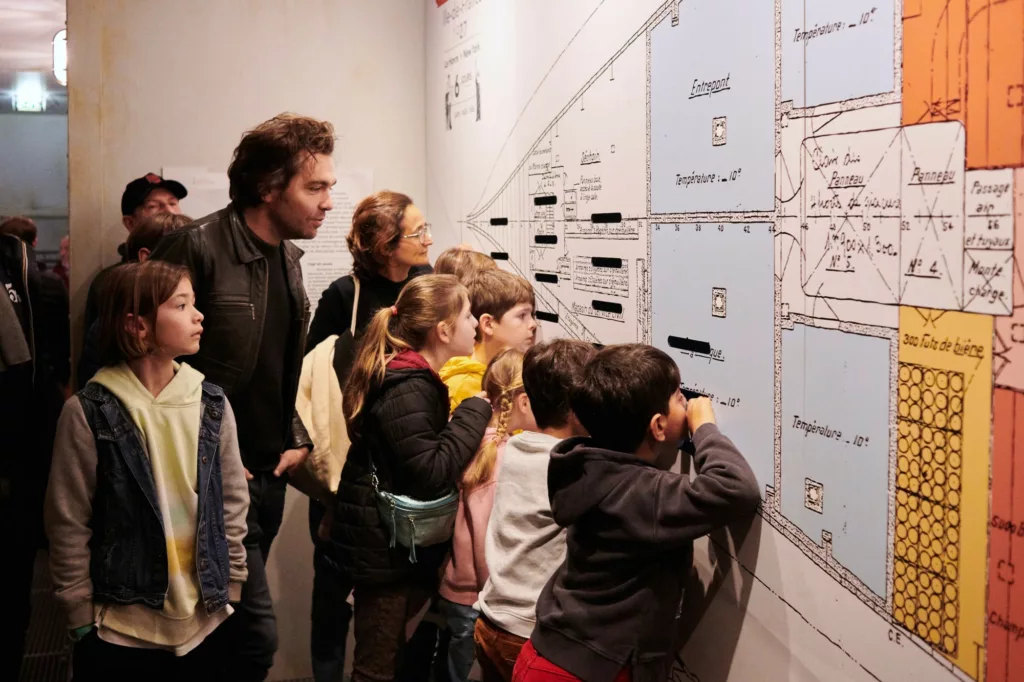 Groupe de visiteurs adultes et enfants dans Escal'Atlantic lors d'une visite guidée.