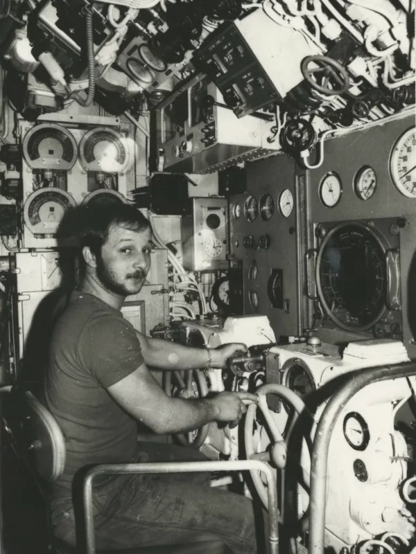 Tirage photographique représentant le sous-marinier Denis Garcia, bosco, aux barres de plongée du sous-marin Espadon dans le poste central.