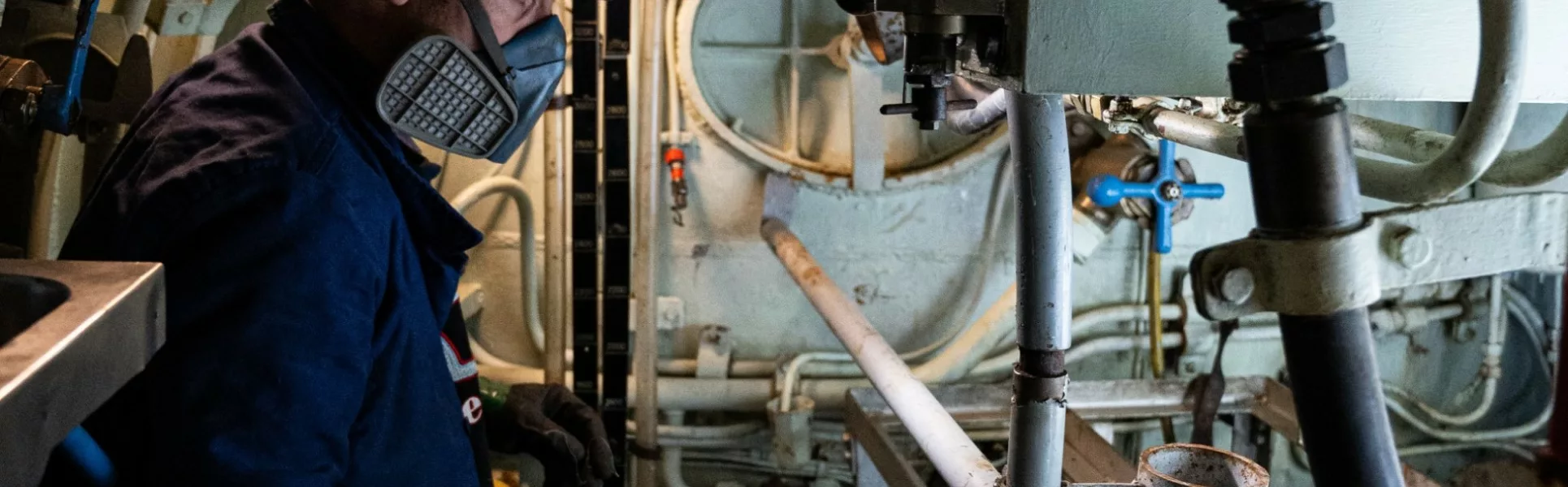Un membre de l'équipe du chantier de restauration équipé d'un masque nettoie l'intérieur du sous-marin Espadon.