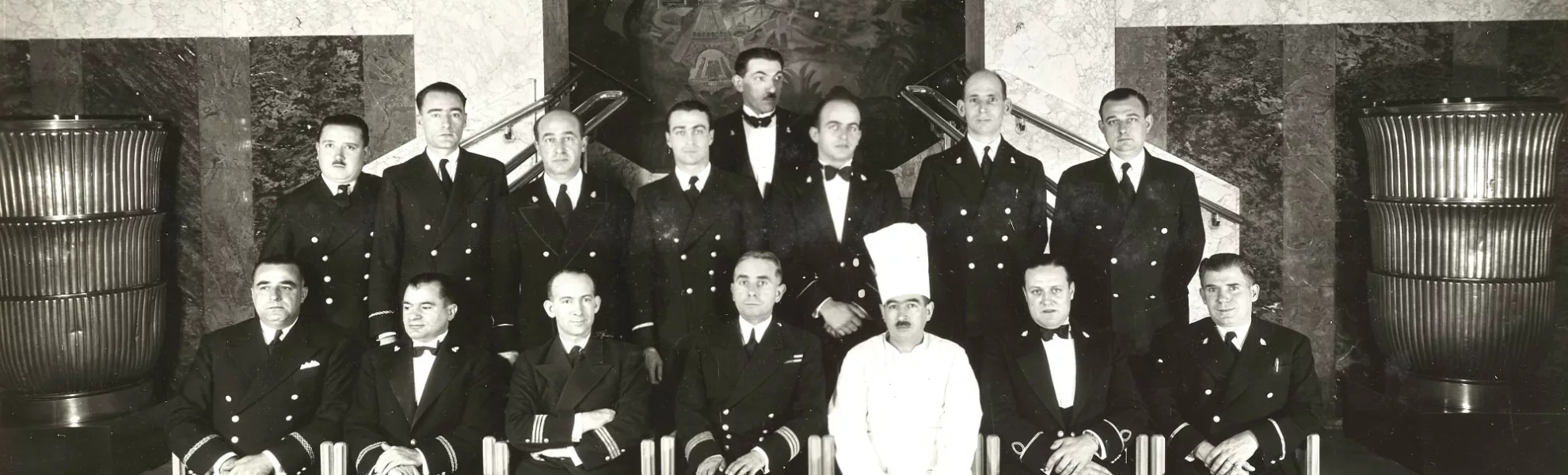 Photographie de groupe des membres d'équipage du paquebot transatlantique Ile-de-France (1927) en octobre 1937 dans la salle à manger du navire.