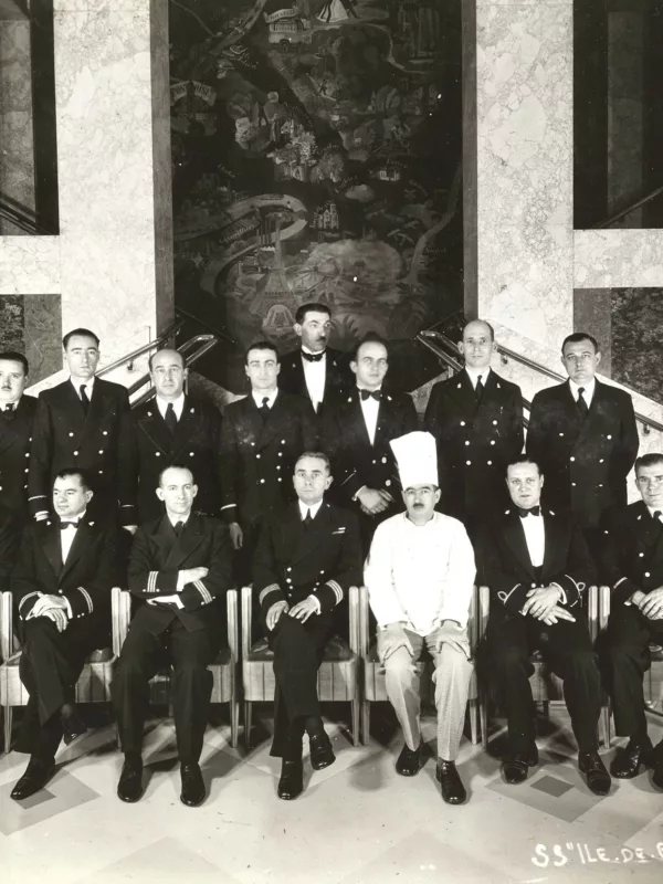 Photographie de groupe des membres d'équipage du paquebot transatlantique Ile-de-France (1927) en octobre 1937 dans la salle à manger du navire.