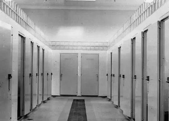 Photographie en noir et blanc d'un couloir avec de chaque côtés des portes à l'intérieur des bains douches de Saint-Nazaire.