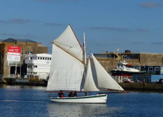 Voilier à coque et voiles blanches navigant dans le bassin de Saint-Nazaire