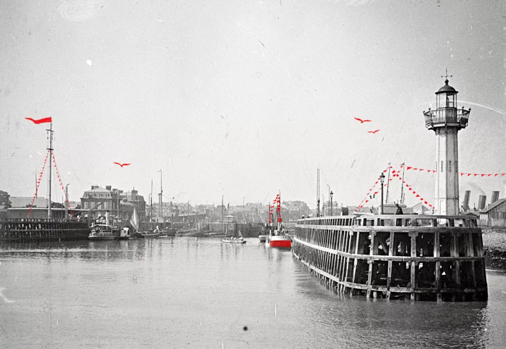 Photographie ancienne en noir et blanc représentant l'entrée est du port de Saint-Nazaire avec à droite l'estacade et son feu de signalisation.