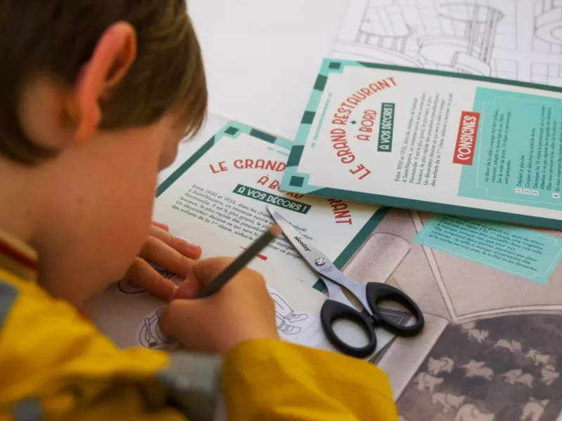 Enfant de dos en train de dessiner pendant le jeu « Le grand restaurant à bord, à vos décors ! ».