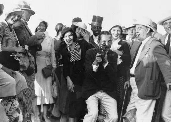 Groupe de personnages posant autour d'un photographe qui fait face à l'objectif.